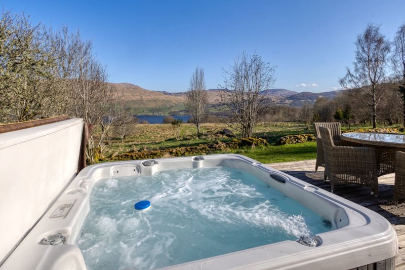 Hot tub on outdoor deck with mountain and lake views, surrounding countryside landscape
