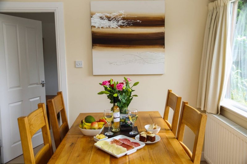 Dining room with wooden table, four chairs, fresh flowers, and wall art
