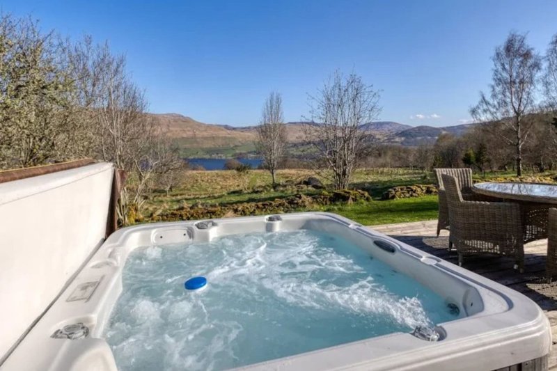 Outdoor hot tub with mountain and lake views, garden furniture nearby