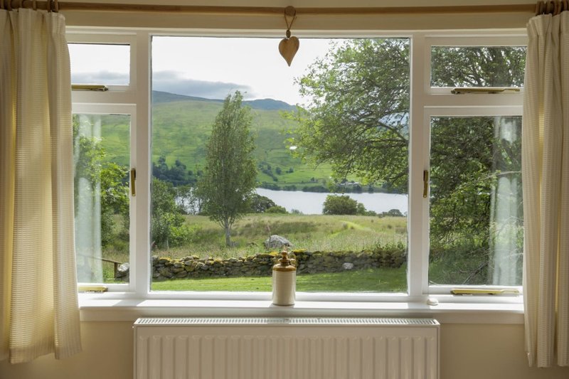 Large window with countryside view of mountains, river, and green fields beyond