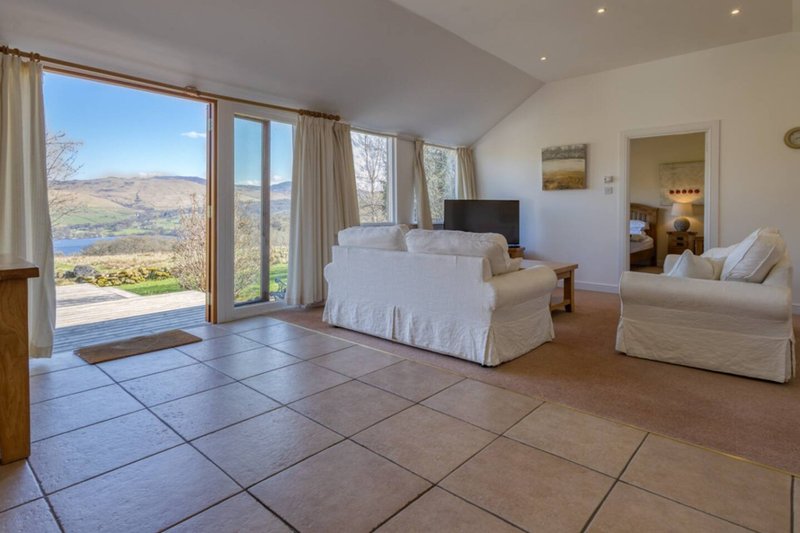 Spacious bedroom with tiled floor, large windows overlooking valley, white furnishings and countryside views
