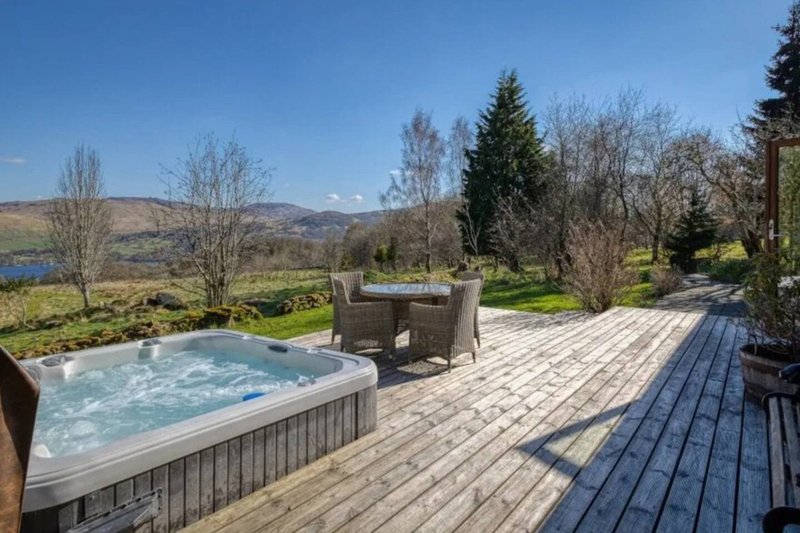 Spacious decking with hot tub, seating area, lake and mountain views