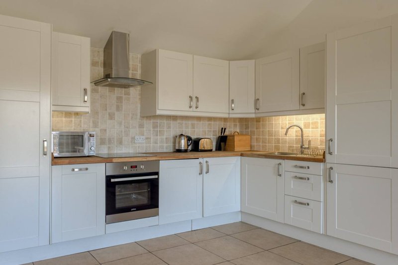Modern kitchen with white cabinetry, tiled backsplash, built-in oven and extractor hood
