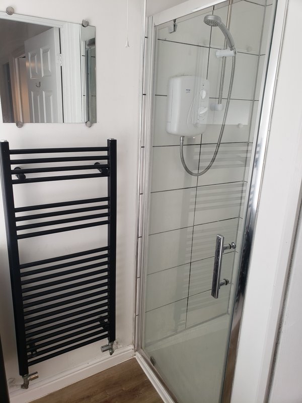 Modern bathroom with walk-in shower enclosure, black heated towel rail and mirror