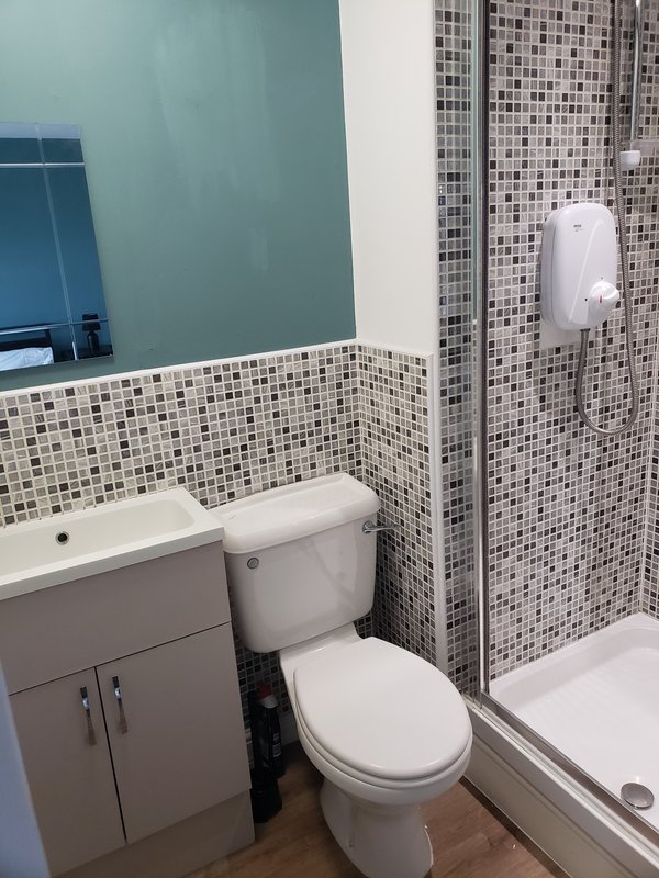 Modern bathroom with vanity sink, toilet, mosaic tile walls and shower enclosure