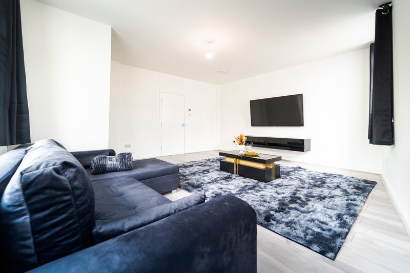 Modern living room with blue sofa, wall-mounted TV, wooden coffee table and area rug