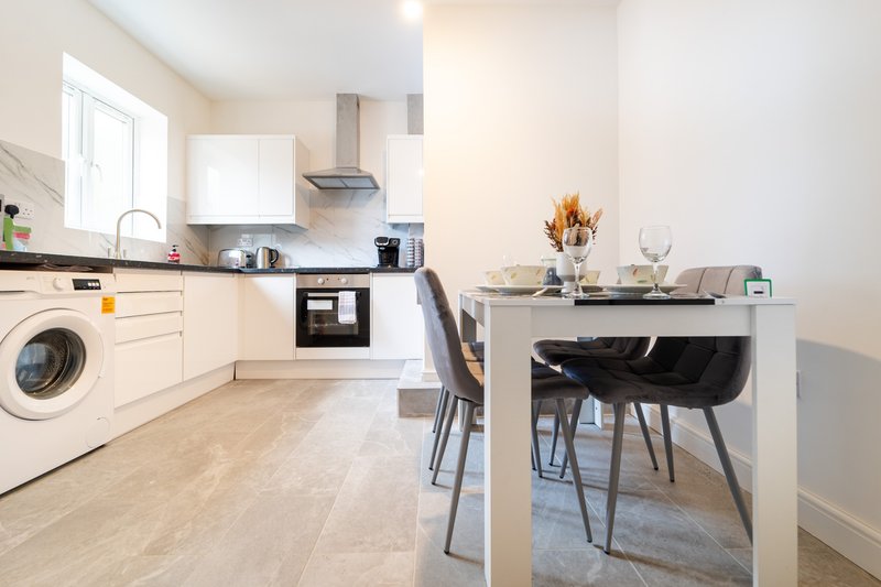 Modern kitchen-diner with white cabinetry, dining table, and washing machine