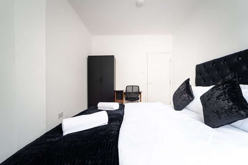 Modern bedroom with twin beds, black headboard, white walls and black wardrobe