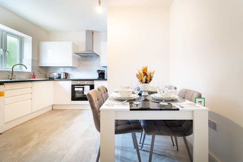 Modern open-plan kitchen and dining area with white cabinetry, dining table, and chairs