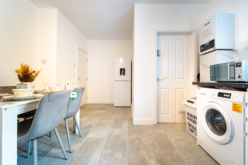 Open-plan kitchen and laundry area with dining chair, washing machine, and microwave