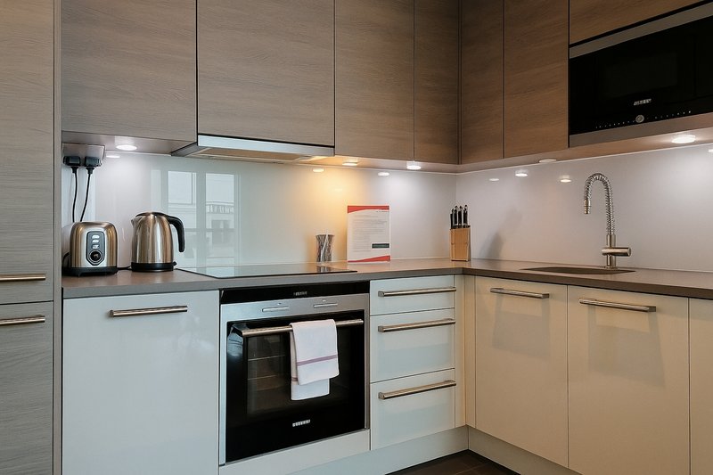 Modern kitchen with light wood cabinetry, electric cooker, kettle and knife block on counters