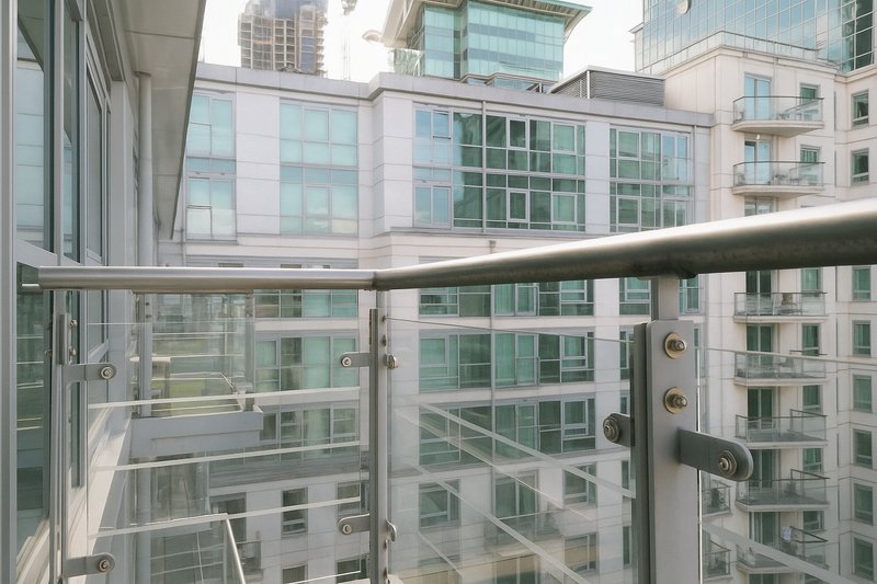 Urban balcony with glass railing overlooking modern apartment buildings and city skyline