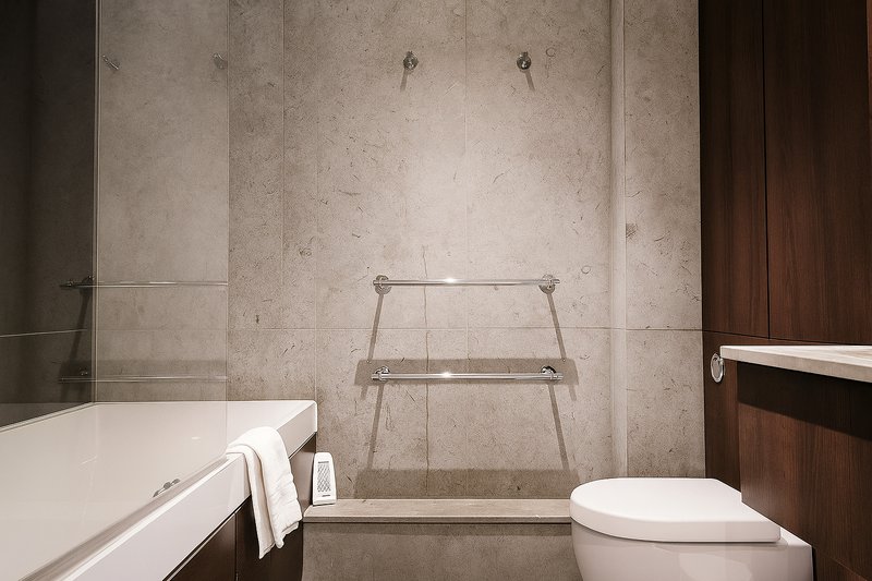 Modern bathroom with white bathtub, toilet, towel rack and tiled shower area