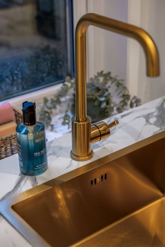 Modern bathroom sink with brass tap, marble countertop and toiletries