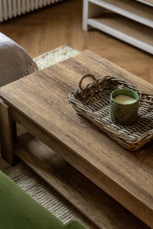 Wooden coffee table with decorative basket, green mug, and woven placemat in living room