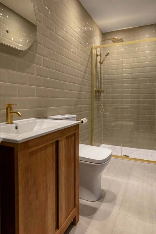 Modern bathroom with white subway tile walls, wooden vanity, white sink, and glass shower enclosure