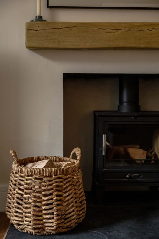 Fireplace with black wood-burning stove, woven basket, and wooden mantel shelf