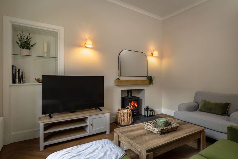 Living room with fireplace, TV, sofa, wooden coffee table and wall shelving