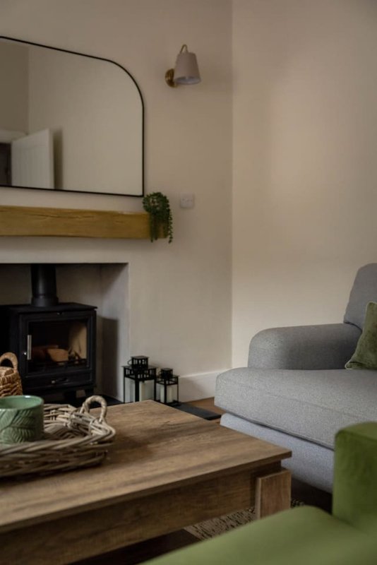 Living room with fireplace, wooden coffee table, grey armchair and arched mirror