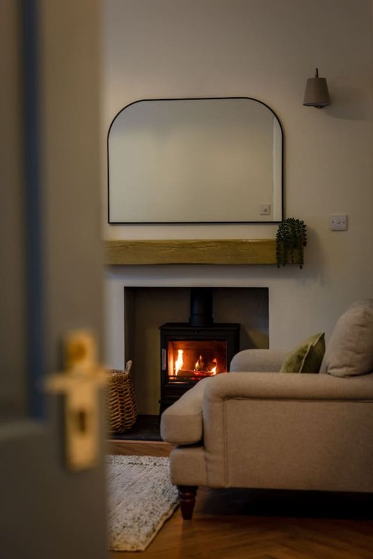 Cozy living room with fireplace, mirror above mantel, upholstered armchair and pendant light