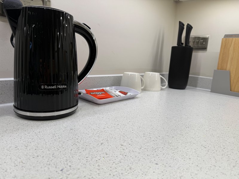 Kitchen counter with black kettle, white mugs, knife block, and decorative items