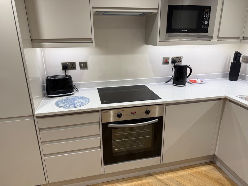 Modern kitchen with white cabinetry, integrated appliances, and wooden flooring