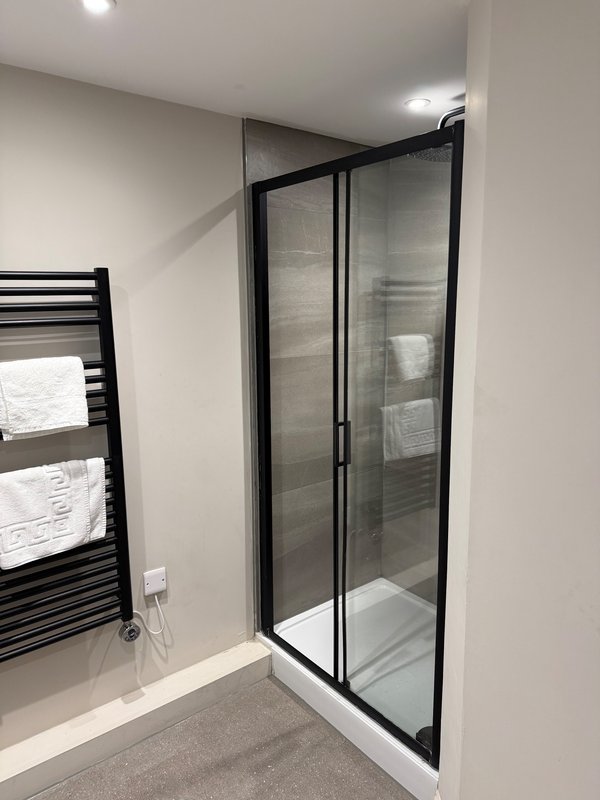 Modern bathroom with black-framed glass shower enclosure and heated towel rail