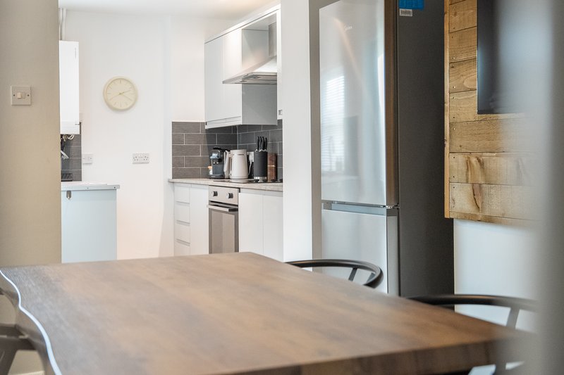 Open-plan kitchen and dining area with wooden table, stainless steel appliances and white cabinetry