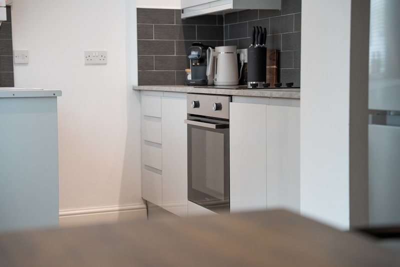 Modern kitchen with white cabinets, stainless steel oven, and dark tile backsplash
