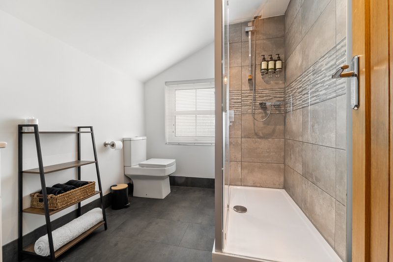 Modern bathroom with walk-in shower, toilet, window and metal towel rack