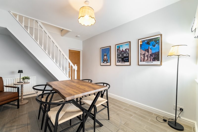 Open-plan dining area with wooden table, black chairs, stairs, and framed wall art