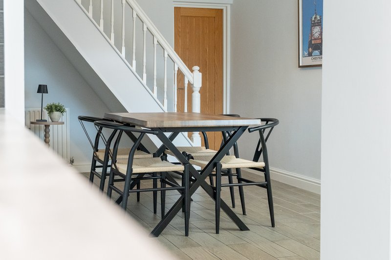 Open-plan hallway and dining area with wooden table, black chairs, and staircase