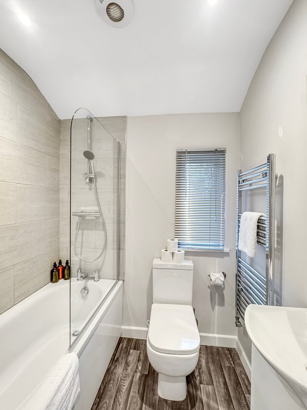 Modern bathroom with toilet, bathtub, shower enclosure, heated towel rail and window