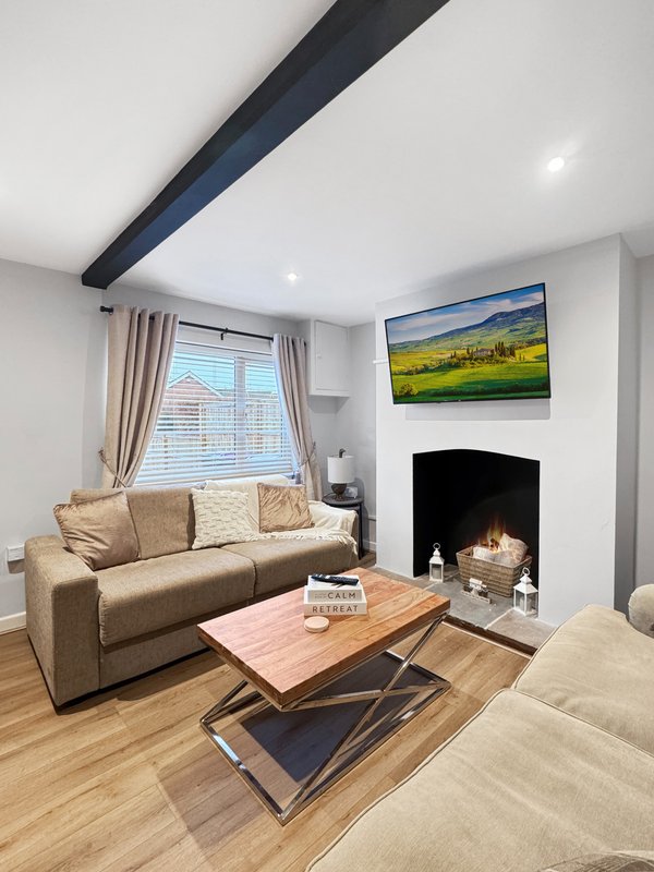 Modern living room with beige sofa, fireplace, wooden coffee table and wall-mounted TV