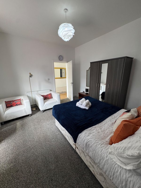 Bright bedroom with two beds, black wardrobe, white sofa and modern pendant light