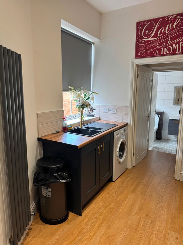 Utility room with black cabinetry, washing machine, countertop with flowers and window above