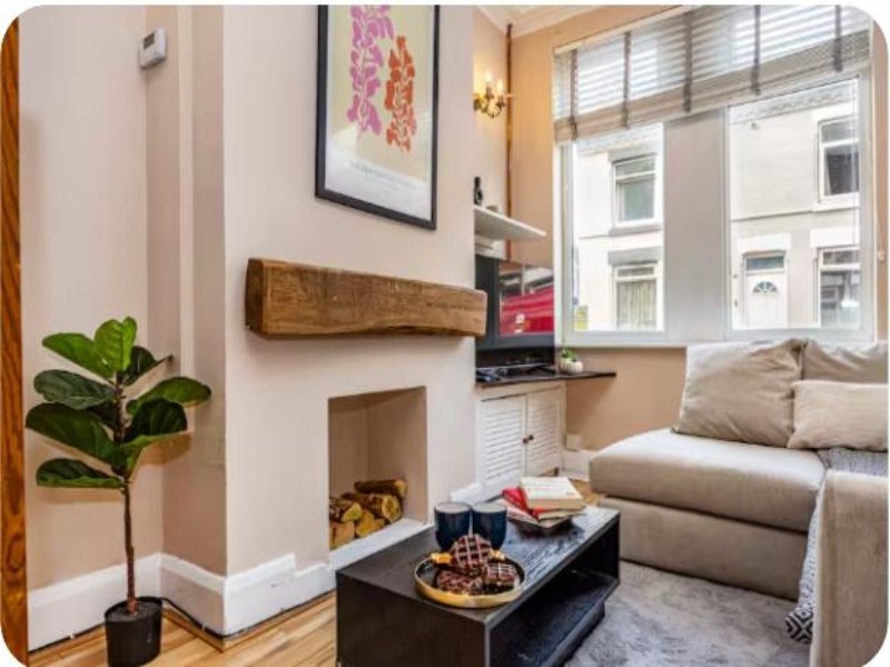 Cozy living room with fireplace, sofa, potted plant, coffee table and street-facing windows
