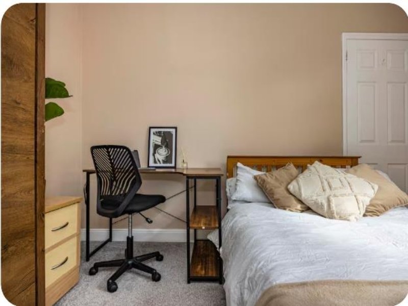 Modern bedroom with double bed, desk workspace, office chair and wooden wardrobe