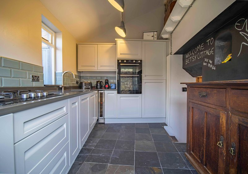 Modern kitchen with white cabinetry, black worktops, built-in appliances and slate flooring