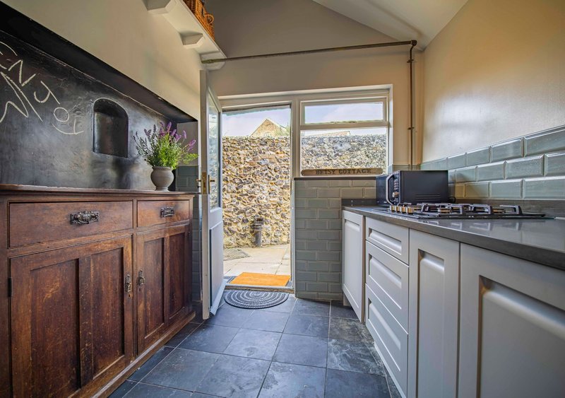 Modern kitchen with white cabinetry, black countertop, stainless steel appliances and garden views
