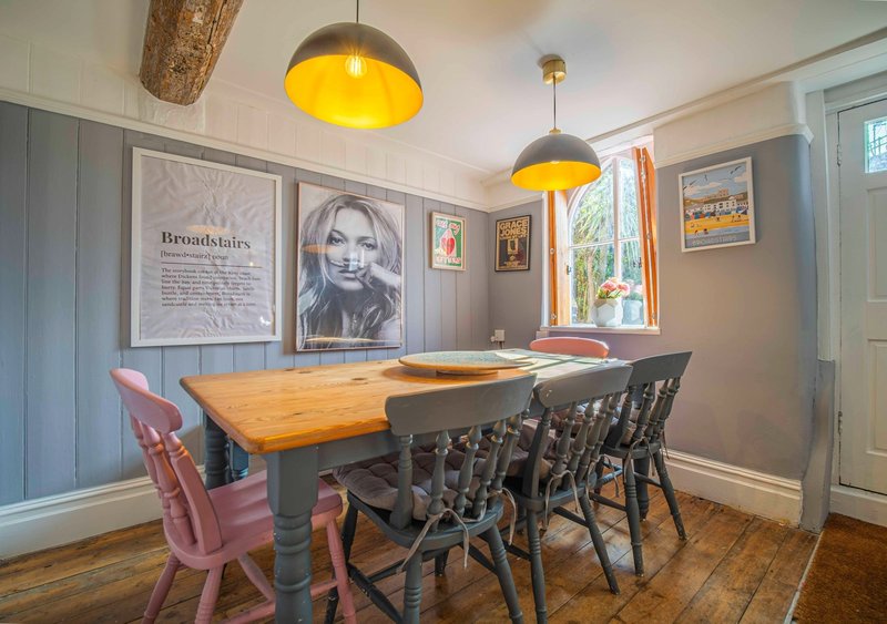 Dining room with wooden table, mixed seating, pendant lights and framed wall art