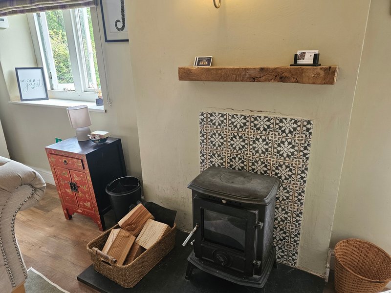 Bedroom corner with wood-burning stove, woven basket, decorative shelf and window