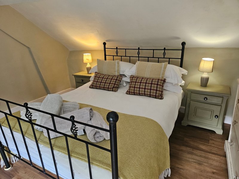 Bedroom with metal-frame double bed, white bedding, plaid pillows, bedside lamps and wooden nightstands