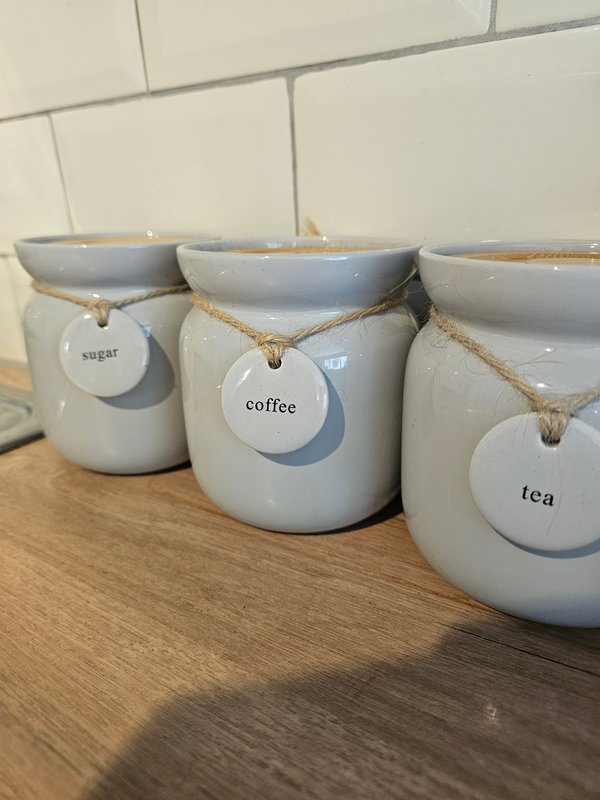 Three ceramic kitchen storage jars with rope handles labeled sugar, coffee, and tea