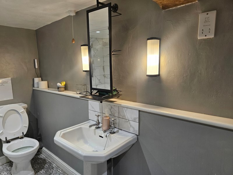 Modern bathroom with grey walls, white sink, mirror, and wall-mounted lighting fixtures