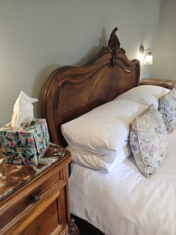 Traditional wooden bed with white bedding, decorative pillows, and carved headboard in bedroom