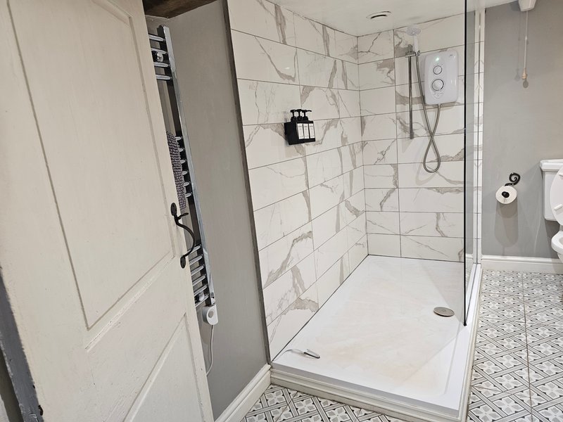 Modern bathroom with walk-in shower, marble tile walls, and patterned floor tiles