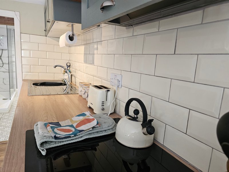Kitchen countertop with white kettle, folded towel, sink and white subway tile backsplash