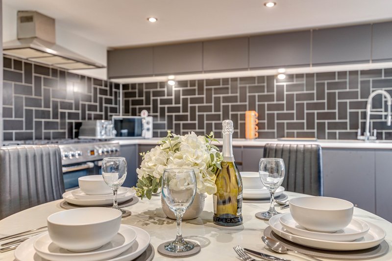 Modern kitchen with dining table set, geometric tile backsplash, and white wine bottle