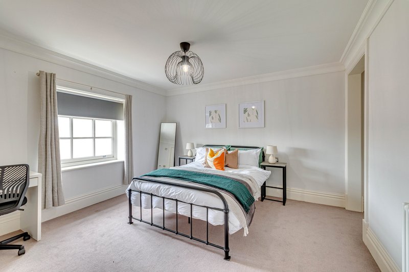 Bright bedroom with metal frame bed, teal bedding, pendant light and large window